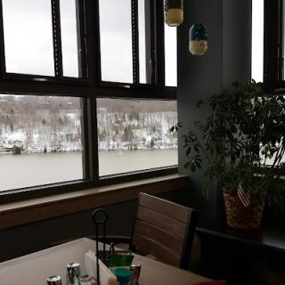 A cozy restaurant interior with a view of the river through large windows.