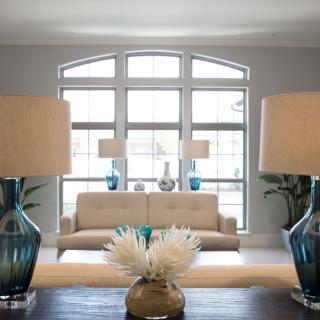 A modern living room with large windows, a comfortable sofa, and blue table lamps.