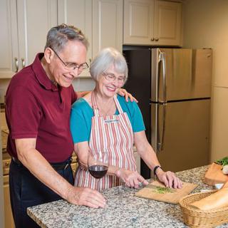 An elderly couple enjoying cooking together in the kitchen.