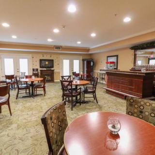 A cozy dining area with wooden tables and upholstered chairs, well-lit and carpeted.