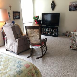 A cozy living room with a rocking chair and a television.