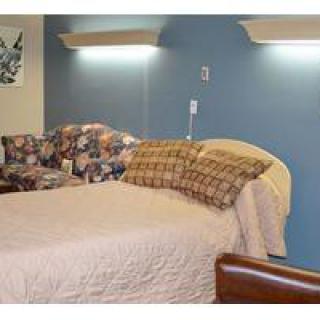 A cozy bedroom with a neatly made bed and ambient lighting.