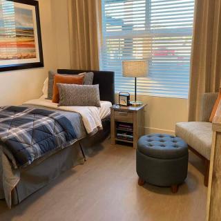 A cozy bedroom with a neatly made bed, stylish decor, and warm lighting.