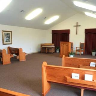 Interior view of a small chapel with wooden pews and an altar.