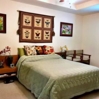 A cozy bedroom featuring a neatly made bed with decorative pillows, wall art, and warm lighting.