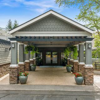 A well-maintained building entrance with a covered walkway and decorative potted plants.