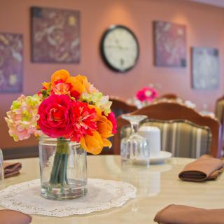 A beautifully set dining table with a vibrant flower centerpiece in a cozy restaurant setting.