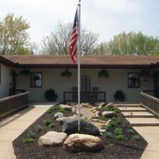 A building with a landscaped garden and an American flag in front.