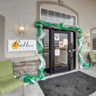 A decorated entrance with green and white adornments at a building with outdoor seating.