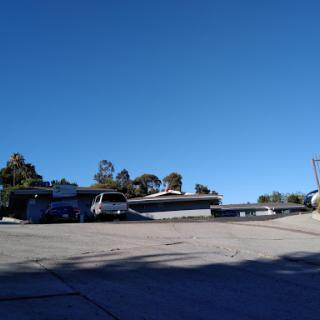 A clear day featuring various vehicles parked along a sloped road under a bright blue sky.