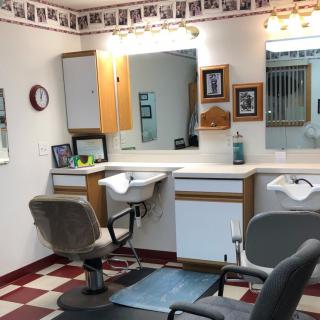 A small barbershop with classic style chairs, mirrors, and bright lighting.