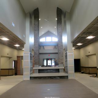 A spacious interior with a modern design, featuring high ceilings and large windows allowing natural light to fill the space.