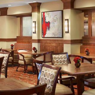 A cozy restaurant dining area with wooden furnishings and modern artwork on the wall.