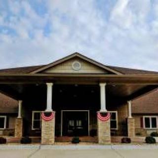 A symmetrical building entrance with columns under a partly cloudy sky.