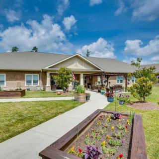 A well-maintained residential building with a garden under a partly cloudy sky.