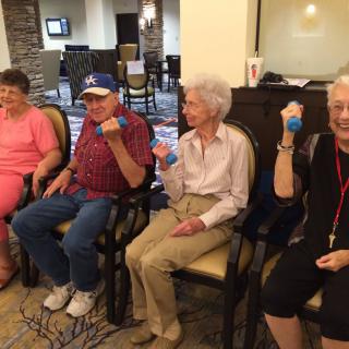 A group of seniors participating in a seated exercise session indoors.