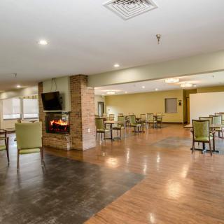 A spacious and modern dining area with a fireplace, featuring tables and chairs on wood flooring.