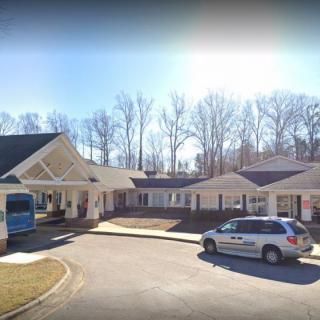 A residential building with parked vehicles in the driveway on a sunny day.