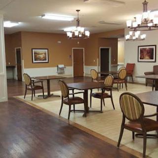 A spacious dining area featuring wooden tables and chairs, with warm lighting and tasteful decor.