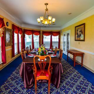 A well-decorated dining room with a large table, elegant chairs, and warm lighting.