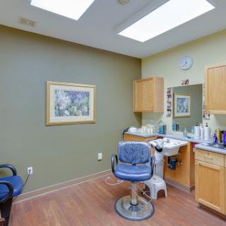 An interior view of a barber shop with a styling chair, mirror, and various hair products.