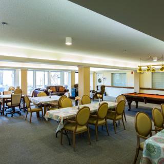 A spacious indoor dining and recreational area with tables, chairs, and large windows.