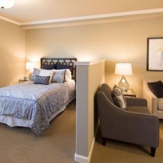 A cozy bedroom with a bed and seating area separated by a partial wall.
