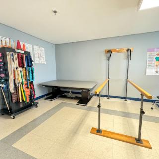 A well-equipped physical therapy room featuring parallel bars and various exercise tools.