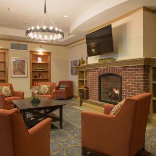 A cozy living room with a brick fireplace, comfortable seating, and warm lighting.