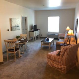 A cozy living room with furniture including a sofa, chairs, tables, and lamps.