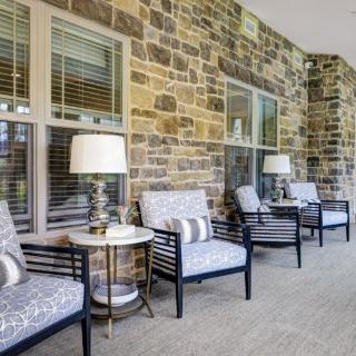 A cozy outdoor patio with comfortable seating and stylish decor against a stone wall.