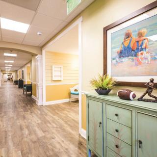 A well-decorated hallway with a wooden floor, featuring furniture and artwork.