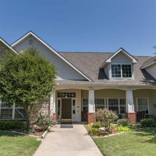 A suburban house with a landscaped front yard and porch under a clear blue sky.