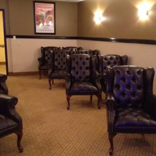 A cozy waiting room featuring upholstered chairs and warm lighting.
