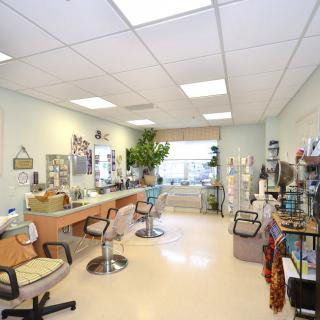 A spacious beauty salon interior with multiple stations, chairs, and various hair and beauty products displayed.
