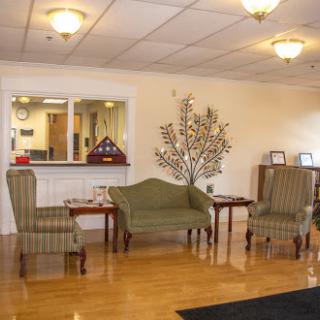 A cozy lobby area featuring a green sofa and striped chairs, perfect for waiting or casual conversations.