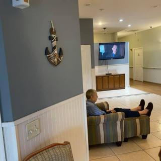 A person is sitting on a couch in a living room watching television.