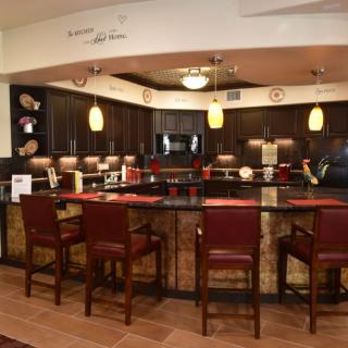 A modern kitchen with a bar counter and stools, featuring dark cabinets and pendant lighting.