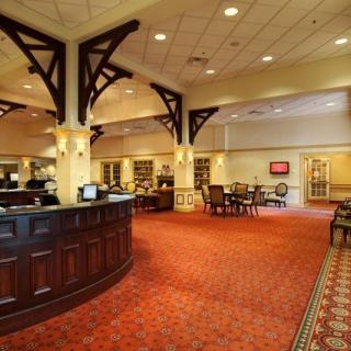A well-lit hotel lobby with a reception desk and seating area.