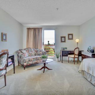 A cozy and well-furnished living space with a sofa, desk, and large window allowing natural light.