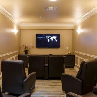 A cozy home theater setup featuring comfortable recliner seating facing a mounted television, complemented by modern lighting and wood flooring.