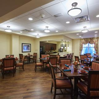 A warmly lit dining area with neatly arranged tables and chairs.