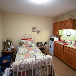 A cozy, compact bedroom with a single bed and an adjoining kitchenette.