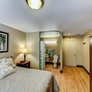 A cozy bedroom with a bed, lamp, and visible bathroom area.