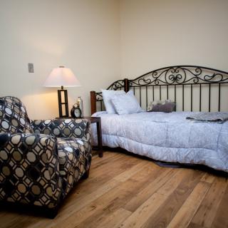 A cozy bedroom with a single bed and patterned armchair.