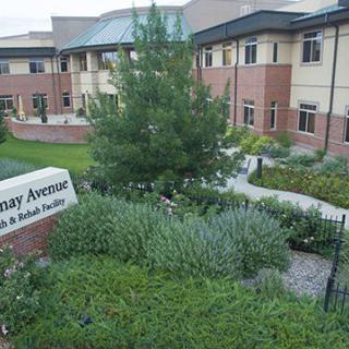 A well-maintained garden in front of a modern building with a pathway and prominent signage.