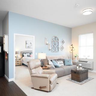 A modern living room with light blue walls, featuring a comfortable sofa, armchair, and a stylish coffee table.