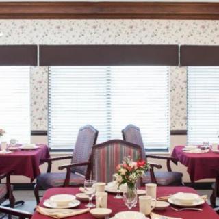 A well-decorated dining room with tables set for a meal, featuring elegant tableware and a floral centerpiece.