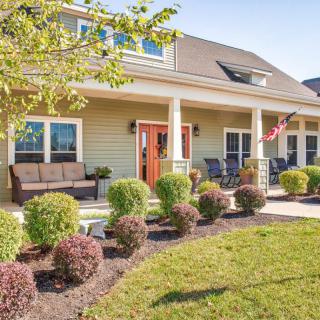 A charming house with a spacious porch and well-maintained landscaping in the front yard.