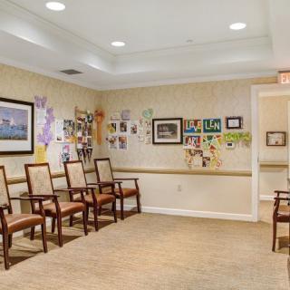 A well-lit waiting room featuring a row of chairs and colorful artwork on the walls.